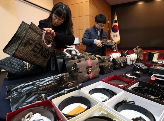 Customs authorities inspect knockoff bags and accessories at the Seoul Main Customs office in Gangnam District, southern Seoul, on Tuesday. The Korea Customs Service seized 142,930 knockoffs in November, of which 25 products that directly make contact with skin were found to contain heavy metals such as lead and cadmium in amounts above the safe level, according to the agency on Tuesday. Knockoff earrings, in particular, were found to contain large amounts of cadmium. [YONHAP]