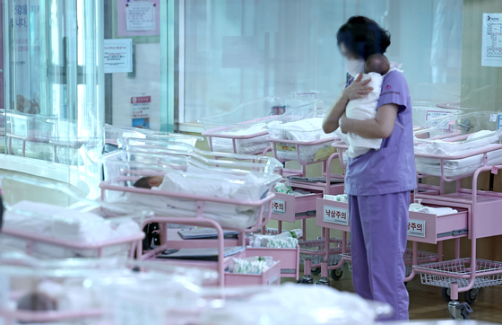 A nurse takes care of a baby at the newborn ward at a public postnatal care center in Seoul. [YONHAP]