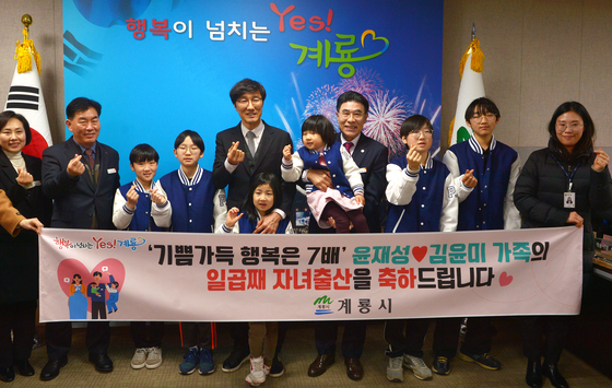 Yoon, center left in the rear row, and six of his seven children take a celebratory photo to celebrate the delivery of the family’s seventh child on Tuesday. The Gyeryong City Government hosted the event. Mayor Lee Eung-wu, center right, holds one of the children. [KIM SEONG TAE / CHOI JONG-KWON]