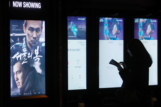 A theatergoer browses film posters displayed at a multiplex cinema in Seoul on Dec. 22, 2023. [YONHAP]