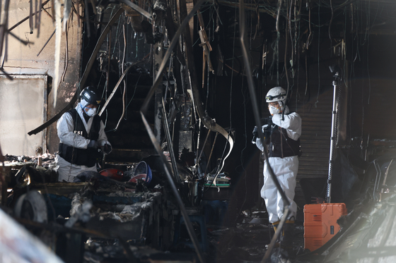 A forensic team on Wednesday inspects the remains of the Seocheon market that was engulfed by a fire two days prior. Some 227 of 292 shops were completely destroyed at the market, which largely specialized in marine products. The government allocated 2 billion won ($1.5 million) on Tuesday to rebuild the market, including the removal of debris. [YONHAP]