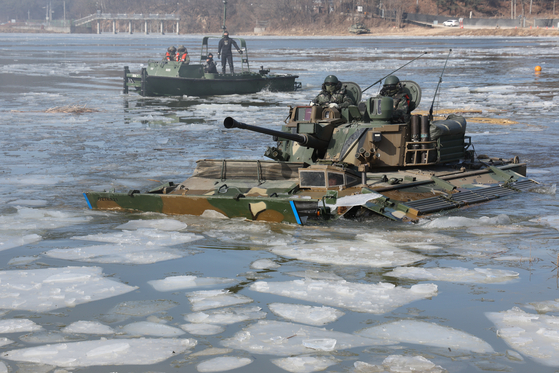 A K21 armored vehicle from the Capital Mechanized Infantry Division navigates a frozen river in Pocheon, Gyeonggi, on Wednesday. The South Korean military drill coincided with North Korea launching multiple cruise missiles into the Yellow Sea on the same day. [YONHAP]