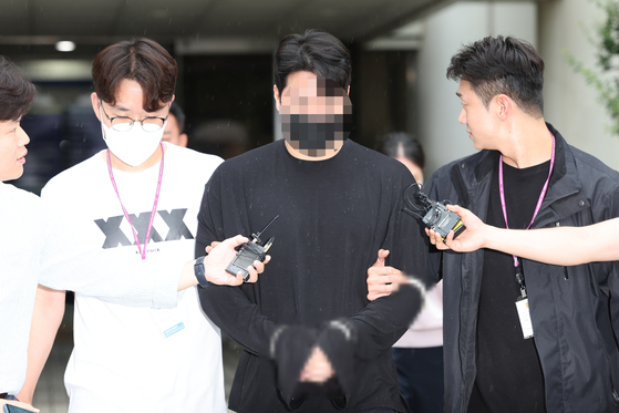 Shin Woo-jun, the driver who ran over a 27 year-old woman with his Rolls-Royce while driving under the influence of drugs, gets escorted by the police to the Seoul Central District Court in southern Seoul on Aug. 11, 2023. [YONHAP]