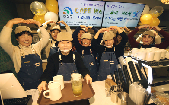 Older workers welcome guests on Wednesday, the grand opening of “CAFE WE_WOORI” inside the community center of an apartment complex in Daejeon. The Korean word ″woori″ means ″we″ or ″us″ in English. The cafe aims to create employment opportunities for older adults and earn profits, which will later be used to boost employment opportunities for older people in the neighborhood. The cafe is managed by Daedeok District Senior Club, a local institution facilitating senior employment in the neighborhood. [NEWS1]