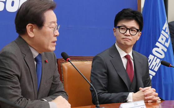 Han Dong-hoon, interim leader of the People Power Party, right, and Lee Jae-myung, leader of the Democratic Party, speak in a meeting at the National Assembly on Dec. 29, 2023. [KIM SEONG-RYONG]