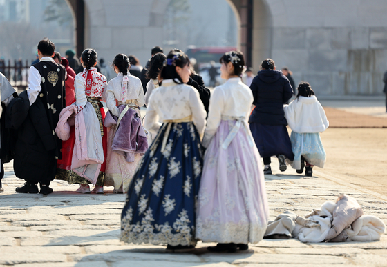 Tourists in traditional clothing without winter coats pose at Gyeongbok Palace in Seoul on Monday. Temperatures have risen considerably since last week's deep freeze. According to the Korea Meteorological Administration on Monday, nationwide temperatures rose to between 3 and 9 degrees Celsius (37 and 48 degrees Fahrenheit). [YONHAP]