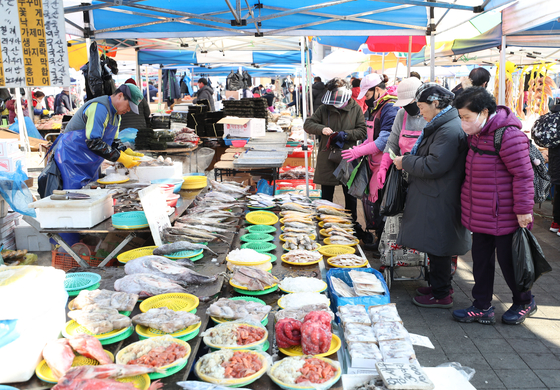 Customers shop for seafood and groceries at the Moran traditional market, which opens once every five days, in Seongnam, Gyeonggi on Monday, ahead of the Lunar New Year holiday. [NEWS1]