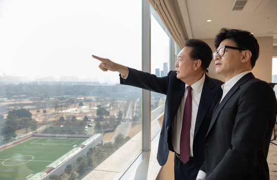 President Yoon Suk Yeol, left, shows People Power Party interim leader Han Dong-hoon the view from his office in Yongsan, Seoul, on Monday. [PRESIDENTIAL OFFICE]