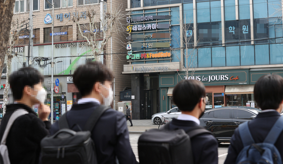 Students wait to cross the street towards a building of private academies, or hagwon, in Daechi-dong of Gangnam District, southern Seoul, on March 4, 2021. [YONHAP] 