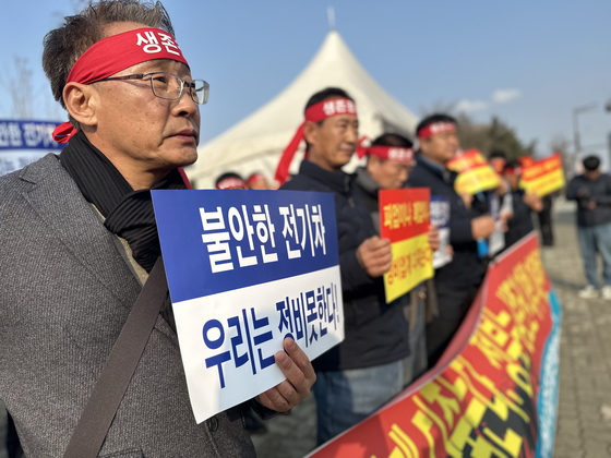 Members of the Korea Automobile Repair & Inspection Federation gathered in front of the National Assembly on Dec. 28 to demand a just transition in automobile industries. The sign in the far right of the picture reads “Unreliable EVs. We cannot repair them!” [CHEON KWON-PIL]