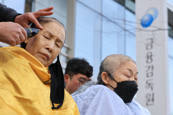 People shave their heads in front of the Financial Supervisory Service in Yeouido, western Seoul to urge compensation for damages related to ELS losses on Jan. 19. [YONHAP]