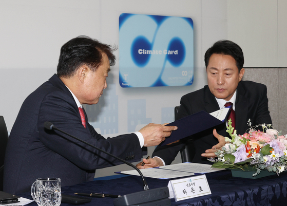 Seoul Mayor Oh Se-hoon, right, and Gunpo Mayor Ha Eun-ho sign an agreement to expand the Climate Card scheme to the southern Gyeonggi city at City Hall in downtown Seoul on Wednesday. [YONHAP]