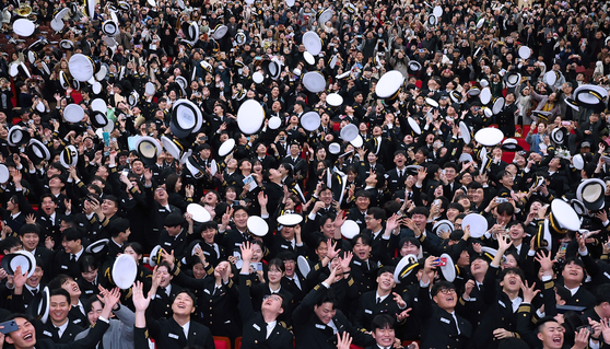 Graduates of the College of Maritime Sciences at the National Korea Maritime & Ocean University in Busan toss their caps at their graduation ceremony on Wednesday. The school has the earliest graduation in the country as male students need to undergo a month of military training between completing their studies and boarding ships. [YONHAP]