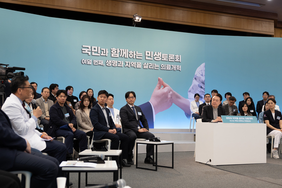 President Yoon Suk Yeol, right, listens to a doctor speak as he presides over a town hall meeting on medical reform at the Seoul National University Bundang Hospital in Seongnam, Gyeonggi, on Thursday, the eighth in a series of public livelihood debates held since the beginning of the year. [PRESIDENTIAL OFFICE]