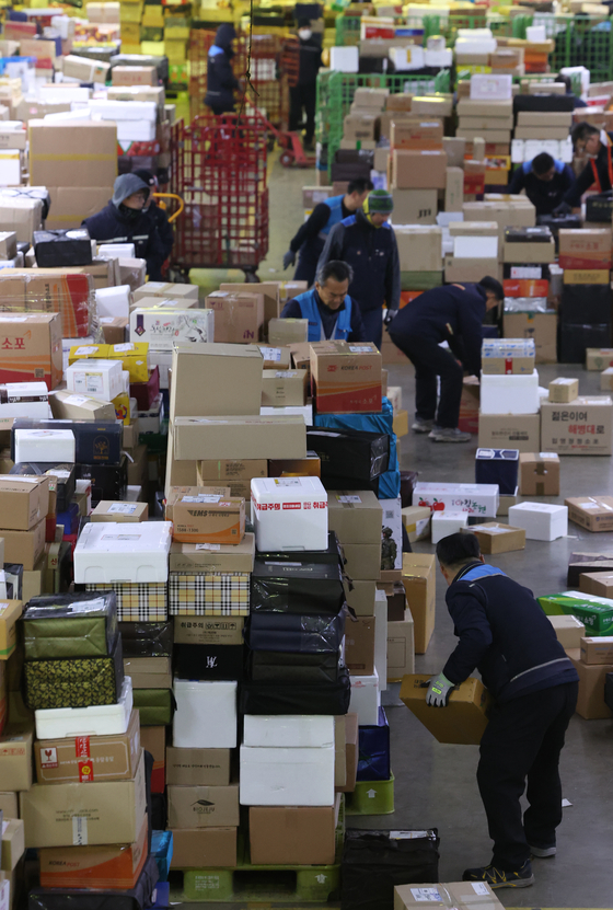 Couriers organize parcels at a logistics center at Gwangjin District, eastern Seoul, on Thursday. [YONHAP]