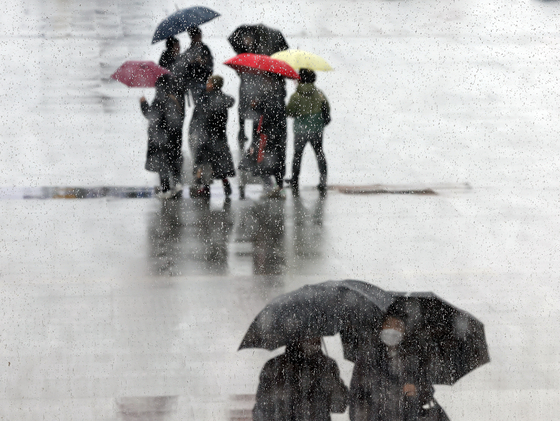 People with umbrellas pass through Gwanghwamun Square in downtown Seoul as rain falls on Jan. 21. [YONHAP] 