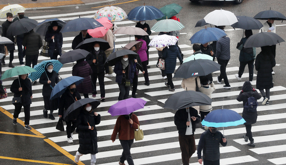 Residents in Busan pass a sidewalk in Dongnae District as rain falls in the area on Monday afternoon. [NEWS1]