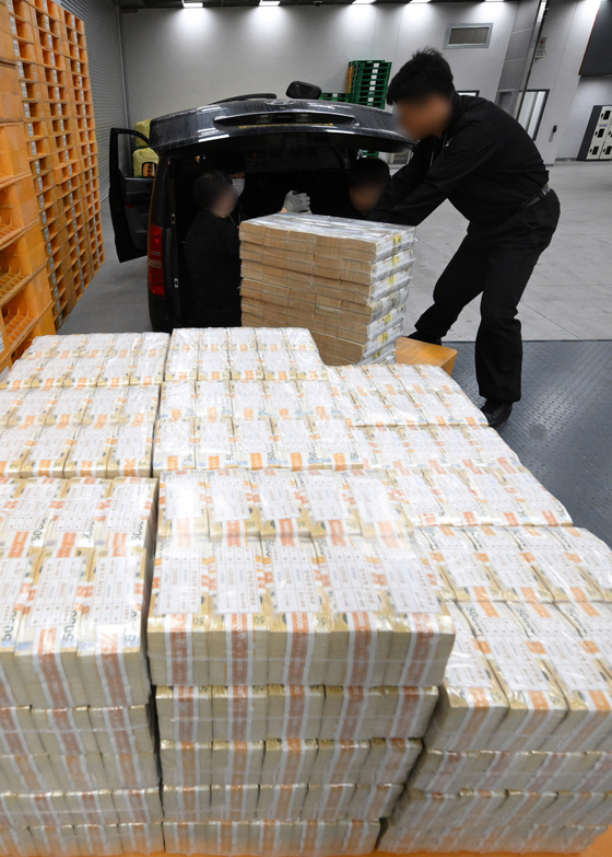 Officials handle the cash that will be distributed to local banks at the head office of the Bank of Korea in Jung District, central Seoul, on Monday. The cash will be given out to bank customers who withdrew savings and funds for the Lunar New Year holiday. [JOINT PRESS CORPS]