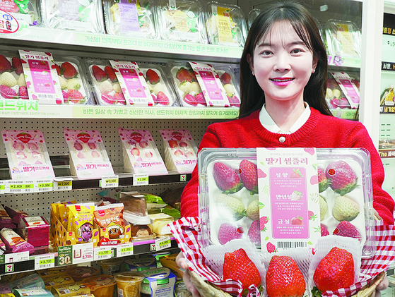 A woman holds a bucket filled with domestically produced strawberries at a 7-Eleven convenience store. [7-ELEVEN] 