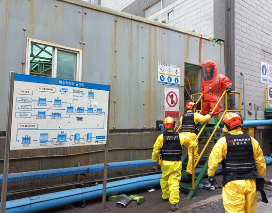 Members of the Incheon Fire Service’s chemical emergency team enter the waste tank at Hyundai Steel’s Incheon plant on Tuesday. Six workers fell unconscious while cleaning the tank. One eventually died. [YONHAP]