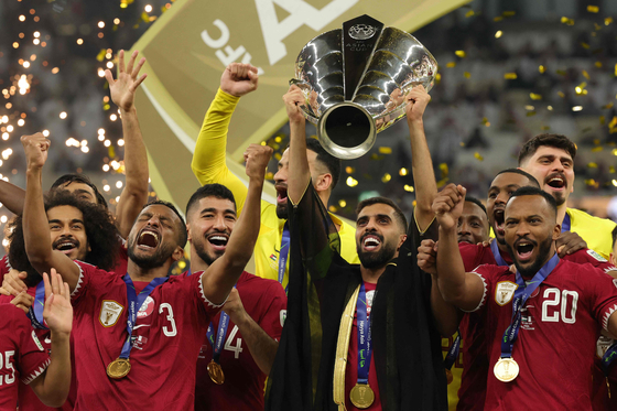 Qatar's Hassan Al-Haydos, center, lifts the Qatar 2023 AFC Asian Cup trophy as his team celebrates during the podium ceremony after the final between Jordan and Qatar at the Lusail Stadium in Lusail, Qatar on Saturday.  [AFP/YONHAP]