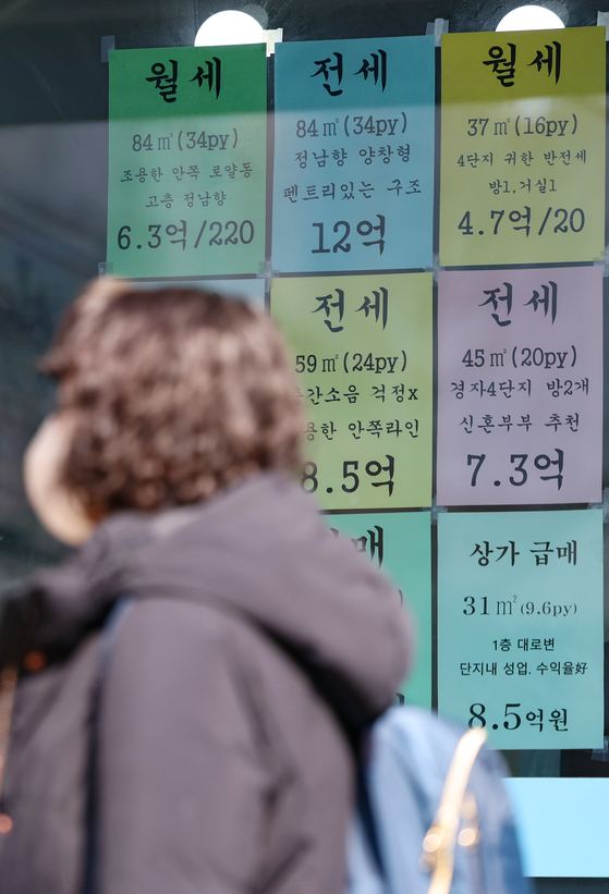 A pedestrian walks past a real estate agency with notices of properties up for  jeonse,  lump-sum deposit contracts, displayed outside in central Seoul on Monday. The monthly ratio of Korea's jeonse price to sales price reached a 10-month high at 66.8 percent in December last year, according to Korea Real Estate Board. In Seoul, the Jongno District in central Seoul ranked top with 62.1 percent. [YONHAP]