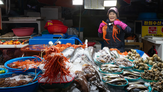 Seafood is a specialty to try out when visiting Mukho in Donghae, Gangwon. A vendor holds up snow crabs at a market stall near Mukho Port. [CHOI SEUNG-PYO]