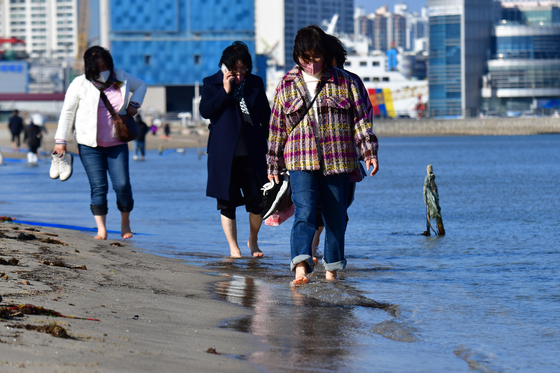 Visitors dip their feet into the waters of Songdo Beach in Pohang, North Gyeongsang, on Tuesday. Pohang's midday high reached 17.9 degrees Celsius (64.2 degrees Fahrenheit) on the same day.[NEWS1]