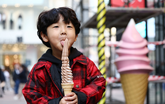 A child licks an ice cream in front of a store in Myeong-dong, central Seoul, on Wednesday as the temperature continues to rise. On Wednesday, the mercury climbed to 18.3 degrees Celsius (64.9 degrees Fahrenheit). Some parts of the country experienced heat reaching up to 20.4 degrees Celsius. However, temperatures are anticipated to plummet overnight as rain is expected. [YONHAP]