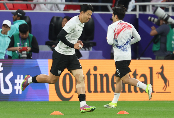 Son Heung-min, left, runs past Lee Kang-in while warming up ahead of the Asian Cup semifinal against Jordan in Qatar on Feb. 6.  [NEWS1]