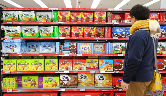 A consumer looks at the stall filled with Korean-made snacks and cookies at a large retailer in Seoul last year. [YONHAP] 