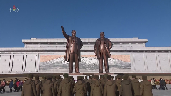 In this footage released by the North's state-controlled Korean Central Television on Friday, residents of Pyongyang pay tribute at the statues of regime founder Kim Il Sung, left, and his son and successor Kim Jong-il, right, to mark the 82nd anniversary of the former's birth. [YONHAP]