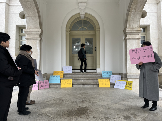 Members of Duksung Women's University's emergency measures committee hold signs in front of the university president's office on Tuesday, condemning the school's decision to shut down the French Language and Literature and German Language and Literature departments. [YONHAP]