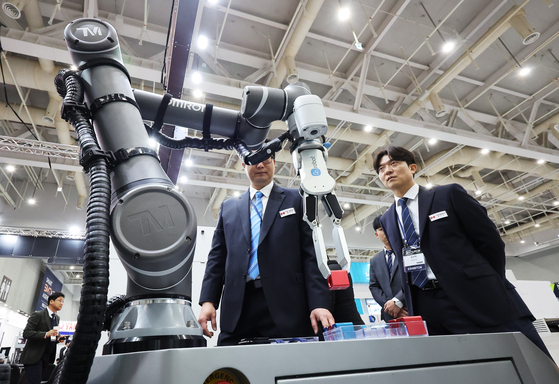 Visitors inspect an electronics manufacturing device displayed at the Smart SMT&PCB Assembly trade show held at Suwon Convention Center in Suwon, Gyeonggi, on Wednesday. [YONHAP] 