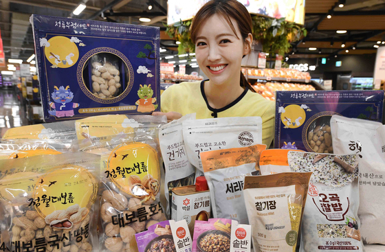 A model shows off bureom, or nuts, and ingredients for ogokbap, or rice with five different grains at a Homeplus branch in downtown Seoul on Wednesday.