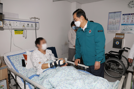 Prime Minister Han Duck-soo talks to an inpatient at National Police Hospital in Songpa District, western Seoul, on Wednesday as trainee doctors continue resigning to protest the government's decision to increase the medical school enrollment quota. [YONHAP] 