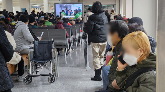 Patients and their guardians sit and wait for their turn at a hospital in Seoul on Wednesday morning. [YONHAP] 