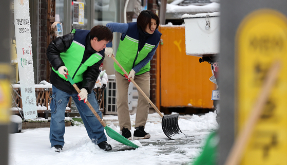 Public officials from Seodaemun District Office in western shovel the snow-covered road in their neighborhood on Thursday morning after heavy snowfall overnight. [NEWS1]