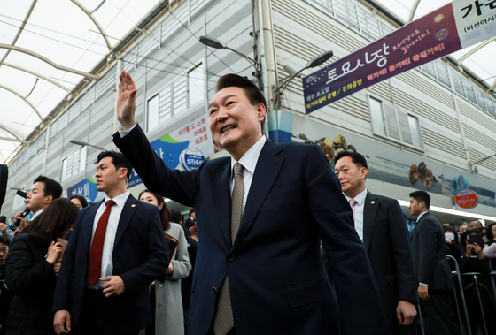 President Yoon Suk Yeol, center, waves his hand to residents and local vendors at the Masan Fish Market in Changwon, South Gyeongsang, on Thursday. [YONHAP] 