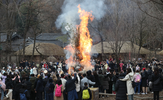 People circle around to watch the burning dalgip, or “moon house,” at the Korean Folk Village in Yongin, Gyeonggi, on Sunday, to mark Jeongwol Daeboreum, a traditional holiday celebrating the first full moon after the Lunar New Year, which fell on Saturday. [NEWS1]