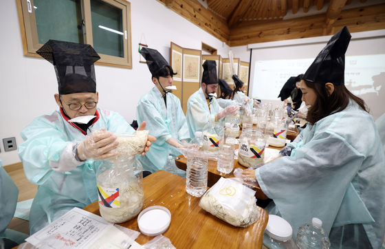 Participants for Local 100 tour try making the sacred liquor sinju at Ojuk Hanok Village on Jan. 26. [MINISTRY OF CULTURE, SPORTS AND TOURISM] 