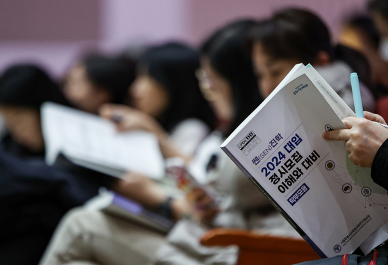 Attendees looks into their guidebook for the 2024 college regular admission during an admissions presentation held in Dongjak District, southern Seoul, on Dec. 11, 2023. [NEWS1]