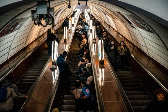Ukrainians take refuge on the escalators of an underground subway station in the center of Kyiv as an alert was issued due to a Russian air strike in late December, 2022. [AFP/YONHAP]