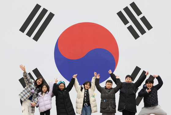 Seven smiling children raise their hands together in front of a large Korean national flag installed at the Seodaemun Prison History Hall in western Seoul on Thursday, a day before March 1 Independence Movement holiday. During the 1910-45 Japanese colonial rule, Korean independence activists were imprisoned at the site. [YONHAP]