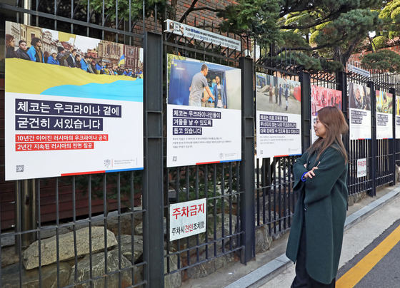 A passerby examines photographs and captions of the exhibition on the Ukraine war held by the Czech Embassy outside of the Czech Center Seoul in Jongno District, central Seoul, on Monday. [PARK SANG-MOON]