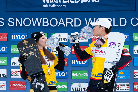 Snowboarder Lee Sang-ho, right, poses with the Crystal Globe alongside Ramona Theresia Hofmeister after becoming the overall winner in men's parallel slalom at the 2023-24 International Ski Federation World Cup in Germany in a photo shared on the FIS official X account on Saturday. Lee's Crystal Globe came after he won a gold medal in Saturday's race in which he surpassed silver medalist Andreas Prommegger of Austria by 0.24 seconds. [SCREEN CAPTURE]