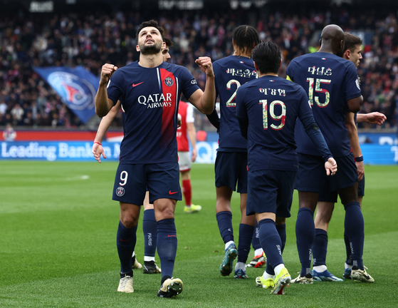 Paris Saint-Germain's Goncalo Ramos celebrates scoring against Reims in Paris on Sunday with Lee Kang-in wearing a hangul shirt visible next to him.  [REUTERS/YONHAP]