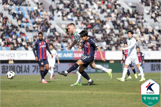 Suwon FC's Lee Seung-woo, center, shoots during a K League 1 match against Jeonbuk Hyundai Motors at Suwon Sports Complex in Suwon, Gyeonggi on Saturday. [YONHAP] 