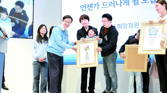 A pediatric cancer patient and families pose for a picture at a symposium about child cancer which was held last November at Seoul National University Hospital in Seoul. [SEOUL NATIONAL UNIVERSITY HOSPITAL] 