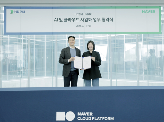HD Hyundai Vice Chairman Chung Ki-sun, left, and Naver CEO Choi Soo-yeon pose for a photo after signing an MOU on the transition to cloud services and commercialization of AI on Monday. [HD HYUNDAI]